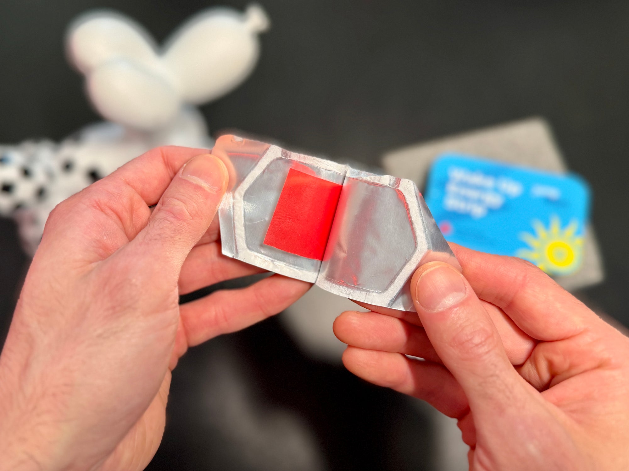 Hands opening a red oral caffeine strip with a blurry background